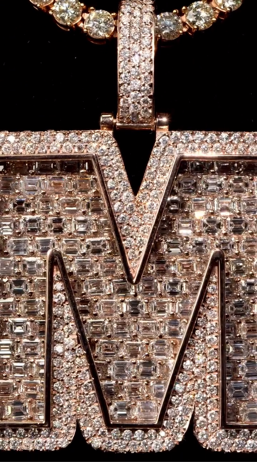 Close-up of the M pendant, emphasizing sparkling Moissanite diamonds and intricate craftsmanship