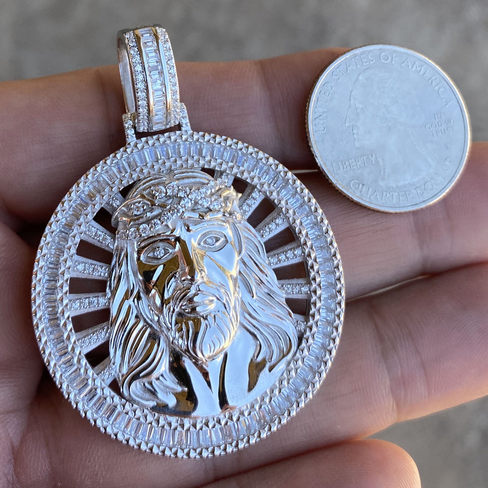 Silver charm Jesus round pendant shown next to a coin for size comparison