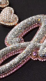 Close-up of custom iced letter pendant paired with heart chain, shimmering Moissanite or CZ stones