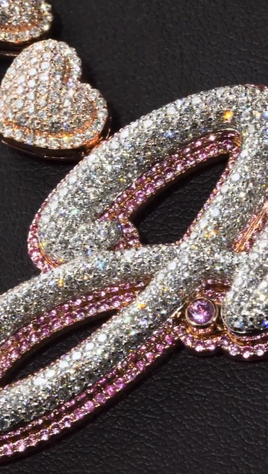 Close-up of custom iced letter pendant paired with heart chain, shimmering Moissanite or CZ stones