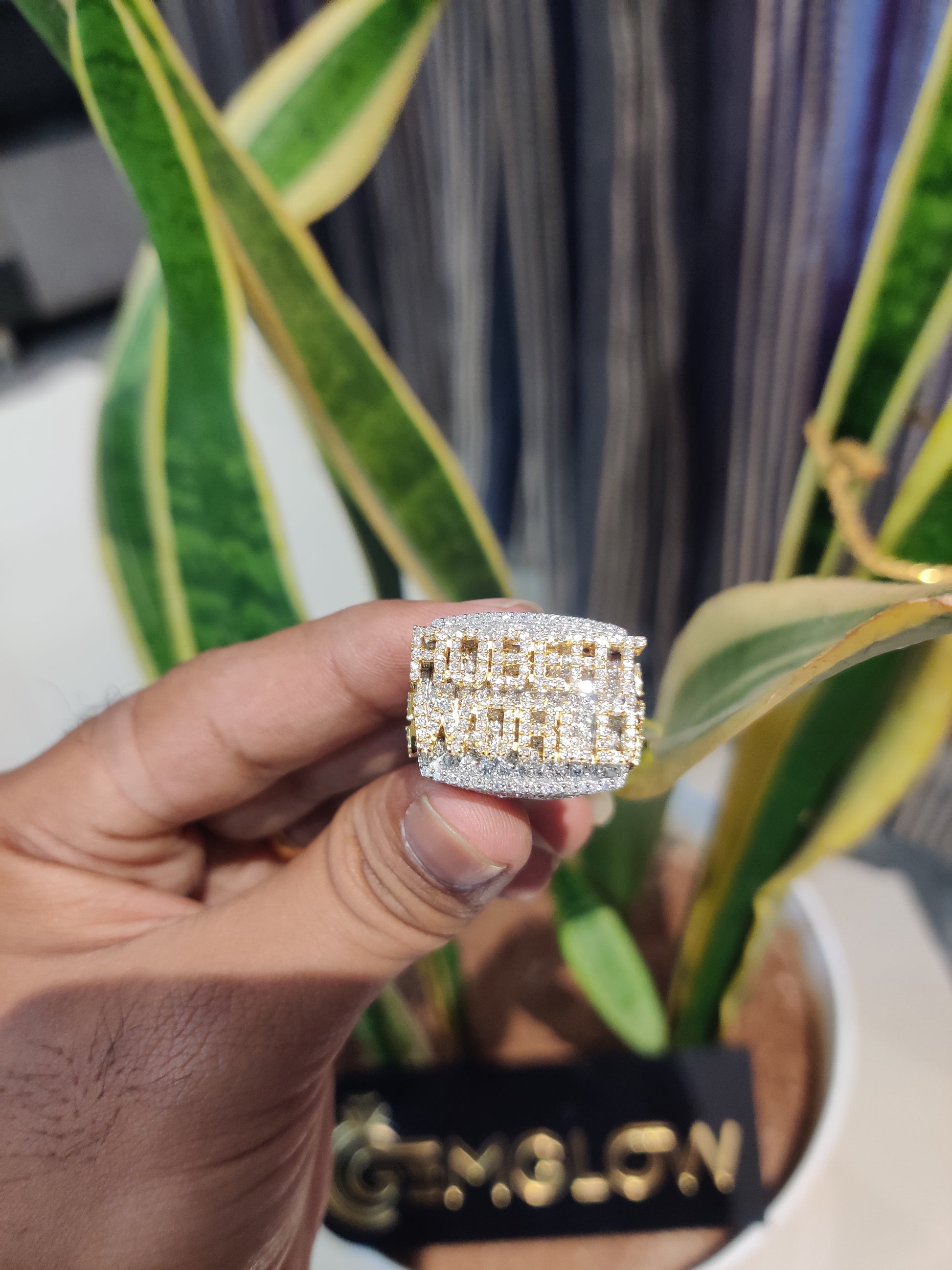 Gold ring held by a hand with a blurred background