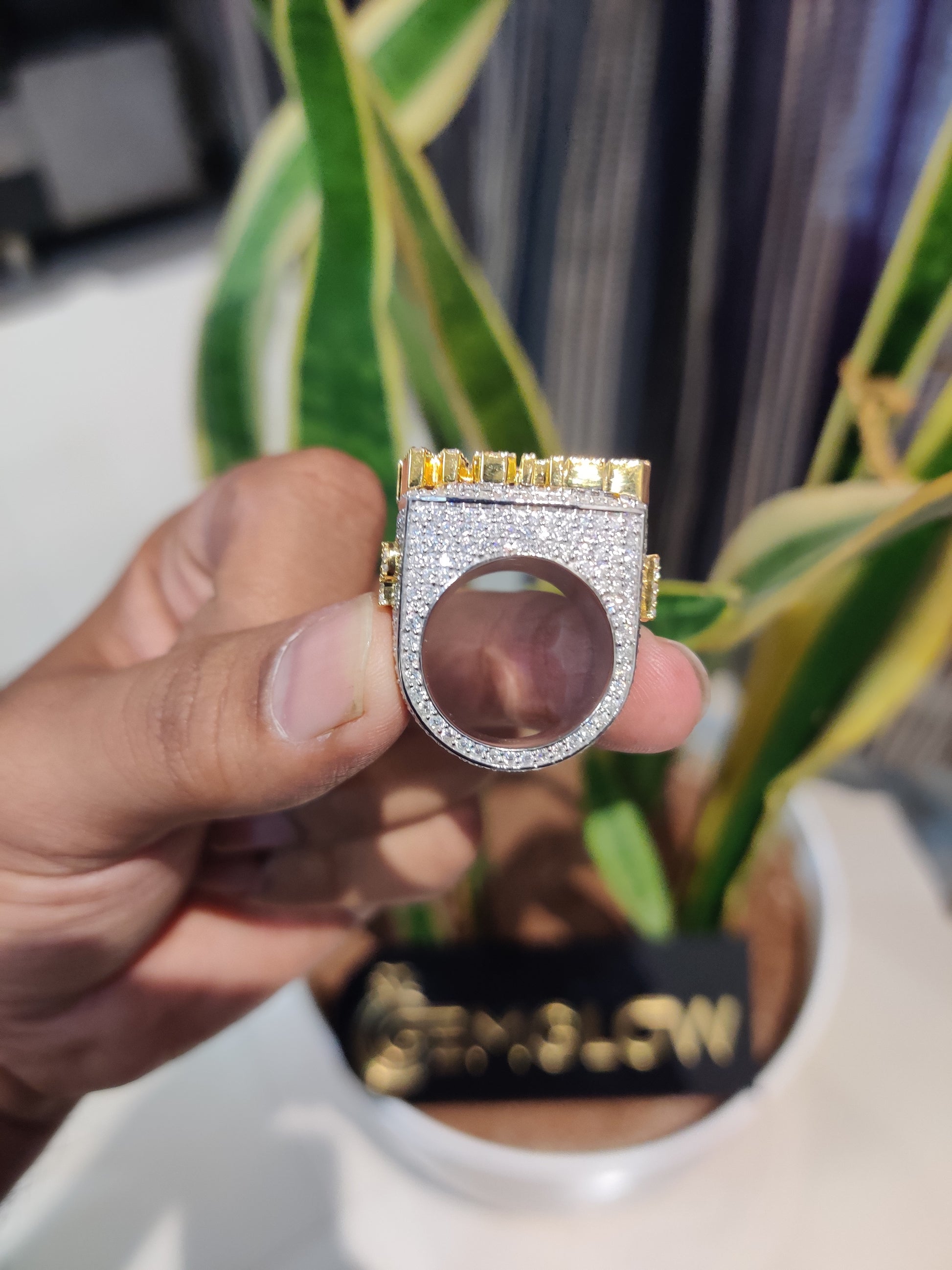 Gold and silver ring held by a hand with a blurred background